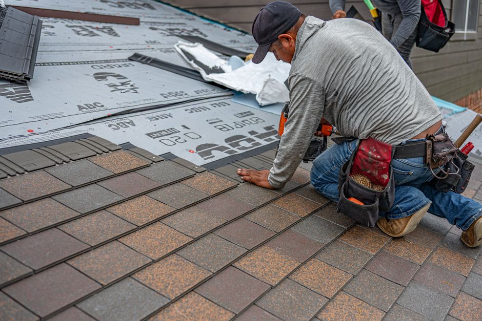 Skilled roofer installing asphalt shingles, ensuring quality home renovation.